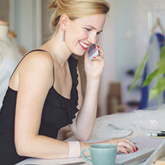 woman sitting a table talking on her cell phone
