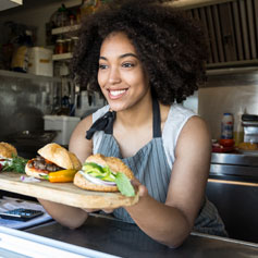 Woman behind counter displaying burgers