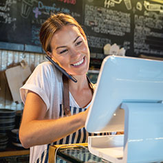 Woman talking on phone smiling while staring at a touch screen