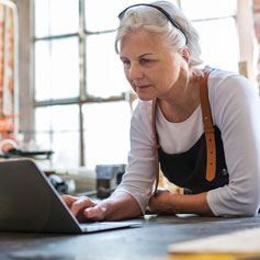 Woman leaning on desk using laptop