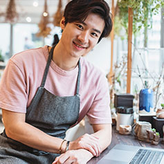 man posing leaning on desk in front of laptop