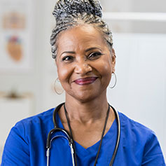 woman in medical attire with stethoscope staring at camera
