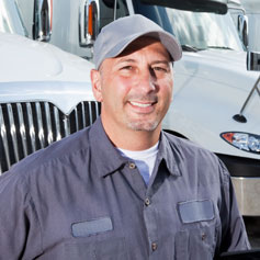 Man in cap in gray work outfit in front of truck