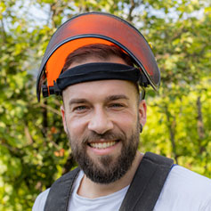 man with heavy duty helmet and face protector smiling at camera