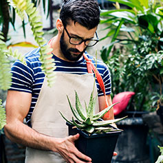 man staring down at plant he is holding