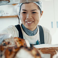woman with hair net reaching in for food